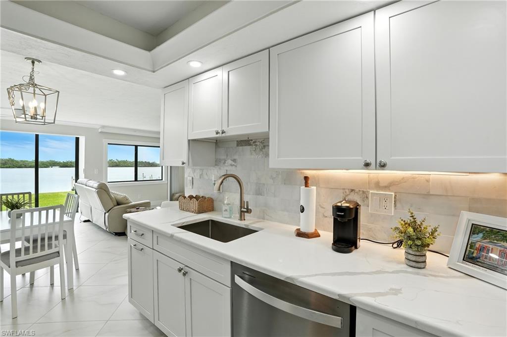 Image 1: Kitchen with recessed lighting, stainless steel dishwasher, white cabinets, decorative backsplash, and a water view