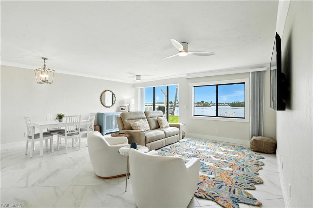 Image 4: Living area featuring ceiling fan, crown molding, light marble finish flooring, and a chandelier