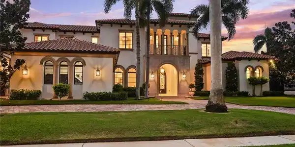 Image 3: Mediterranean / spanish-style home featuring a balcony, stucco siding, a lawn, curved driveway, and a tile roof