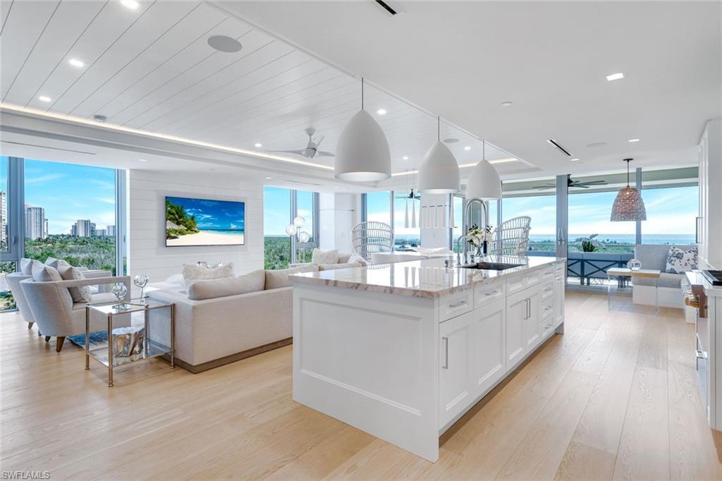 Image 3: Kitchen featuring open floor plan, white cabinetry, hanging light fixtures, expansive windows, and light wood finished floors