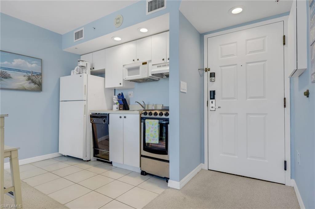 Image 2: Kitchen with white cabinetry, stainless steel range with electric stovetop, light carpet, light countertops, and recessed lighting