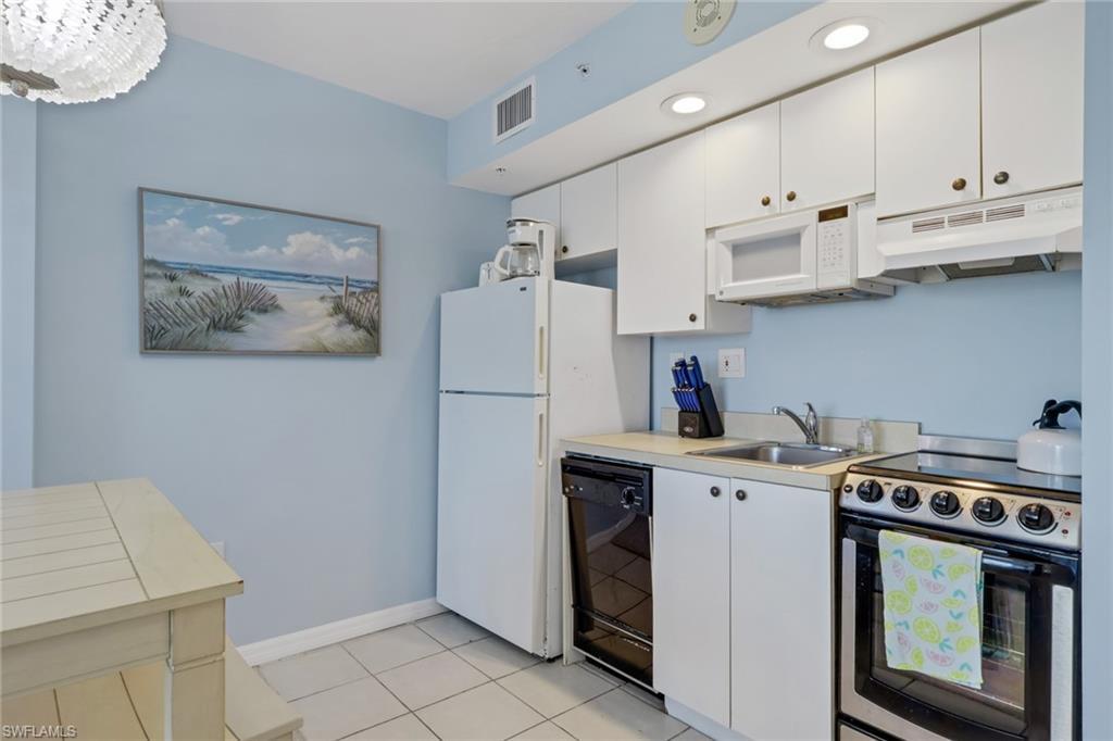 Image 4: Kitchen with white appliances, white cabinets, light countertops, and under cabinet range hood