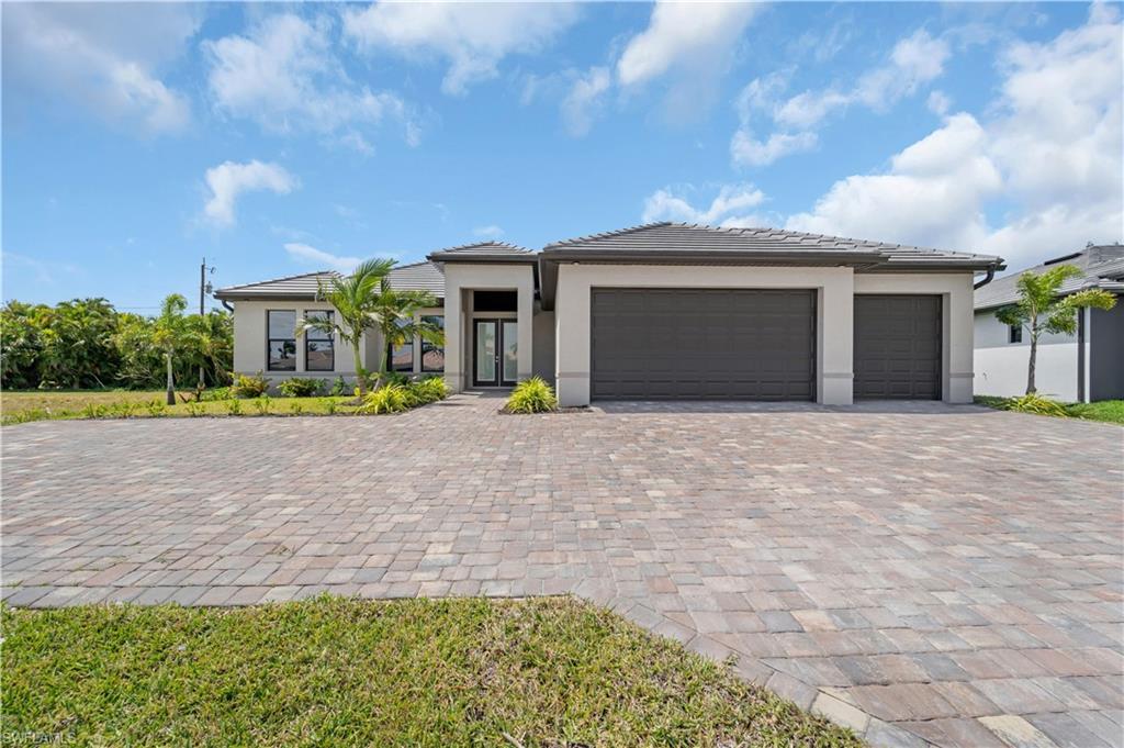 Image 2: Prairie-style home featuring a garage, decorative driveway, and stucco siding