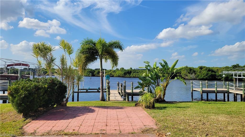 Image 3: Dock area featuring a water view, a lawn, and boat lift