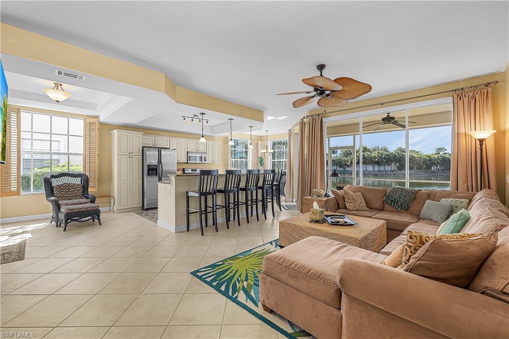 Image 4: Living room with a water view, plenty of natural light, light tile patterned floors, and a ceiling fan