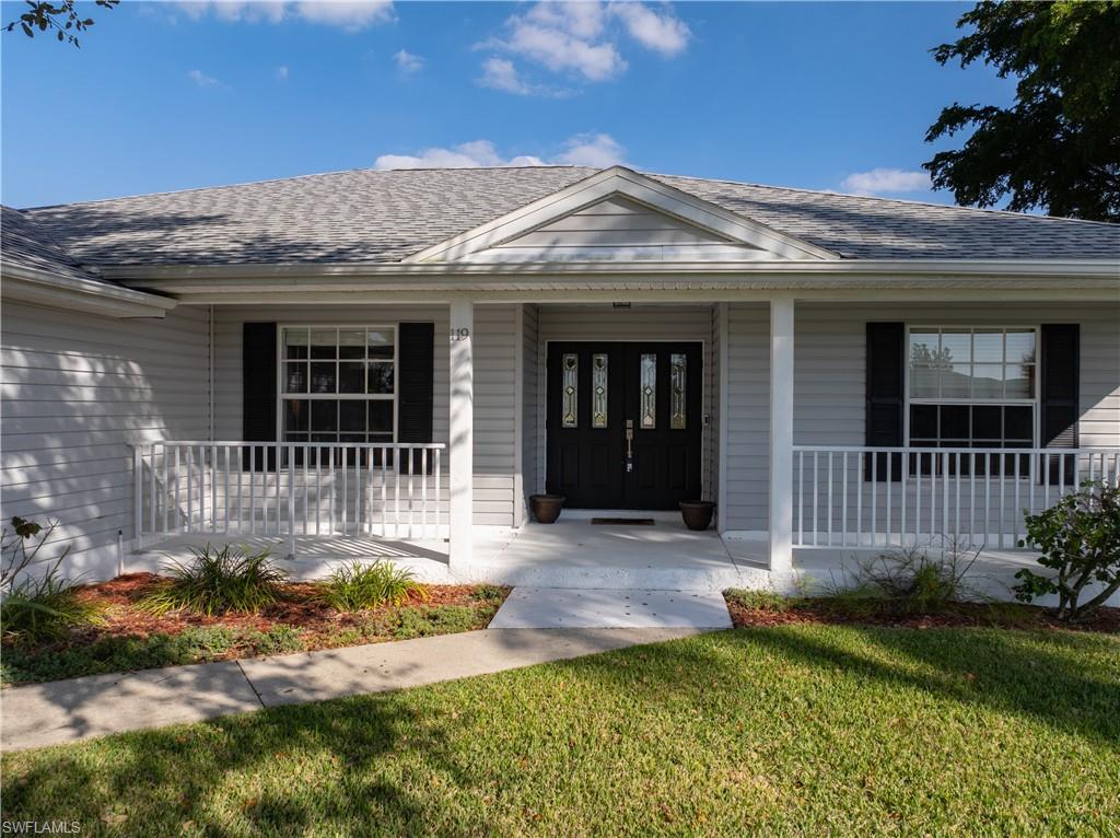 Image 2: Doorway to property featuring a porch, roof with shingles, and a yard