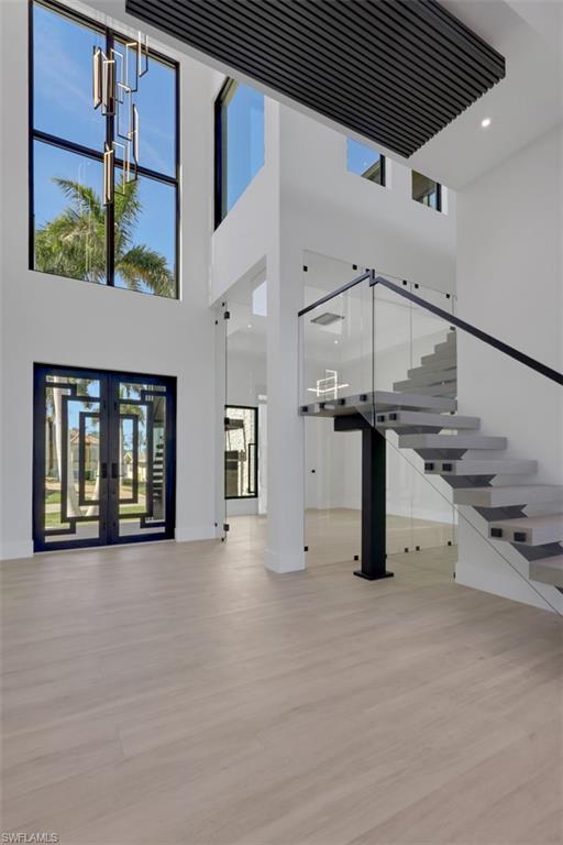 Image 3: Foyer, floating stairs and double 12' high glass doors to den or formal dining room