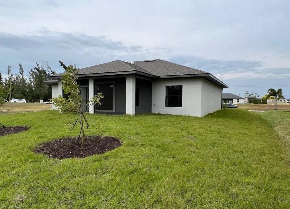 Image 3: Rear view of property featuring a yard, stucco siding, roof with shingles, and a patio area