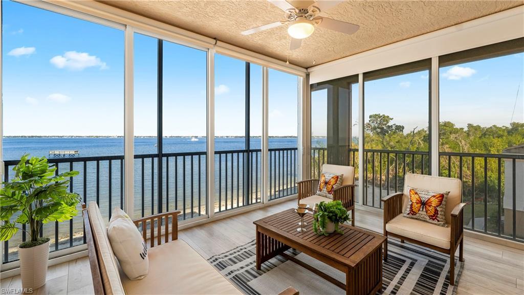 Image 2: Sunroom featuring floor to ceiling windows, hardwood / wood-style flooring, a water view, and a textured ceiling