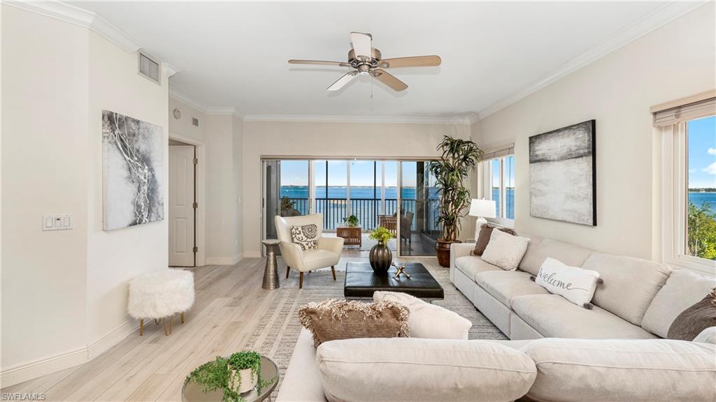 Image 3: Living room featuring wood finished floors, ornamental molding, a water view, ceiling fan, and plenty of natural light