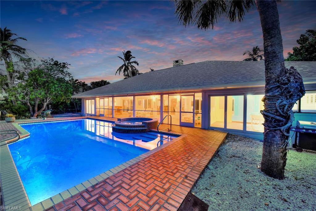 Image 2: Pool at dusk with area for grilling, a patio, and an in ground hot tub