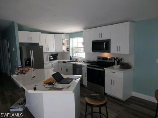 Image 4: Kitchen featuring a breakfast bar, appliances with stainless steel finishes, sink, and white cabinetry