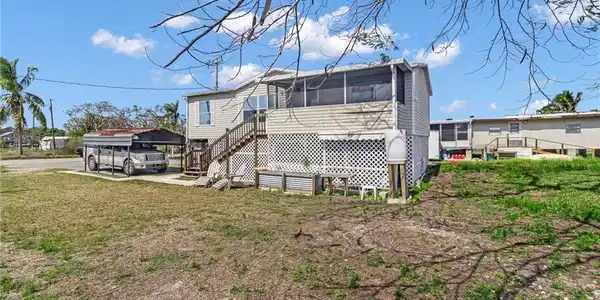 Image 3: Back of property featuring a sunroom, a yard, and stairs