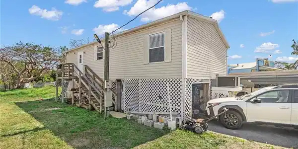 Image 4: View of property exterior with stairs and a lawn