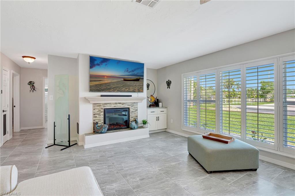 Image 3: Living room featuring plenty of natural light, baseboards, and a glass covered fireplace