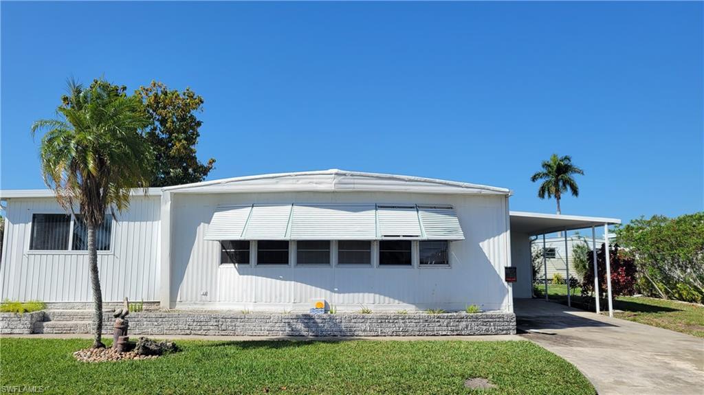 Image 1: Manufactured / mobile home featuring driveway, a front yard, and an attached carport