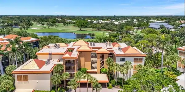 Image 3: Aerial view of a local golf course, a nearby body of water, and a tree filled landscape