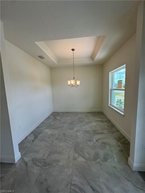 Image 4: Unfurnished dining area featuring a raised ceiling, marble look tiles, crown molding, a chandelier, and baseboards