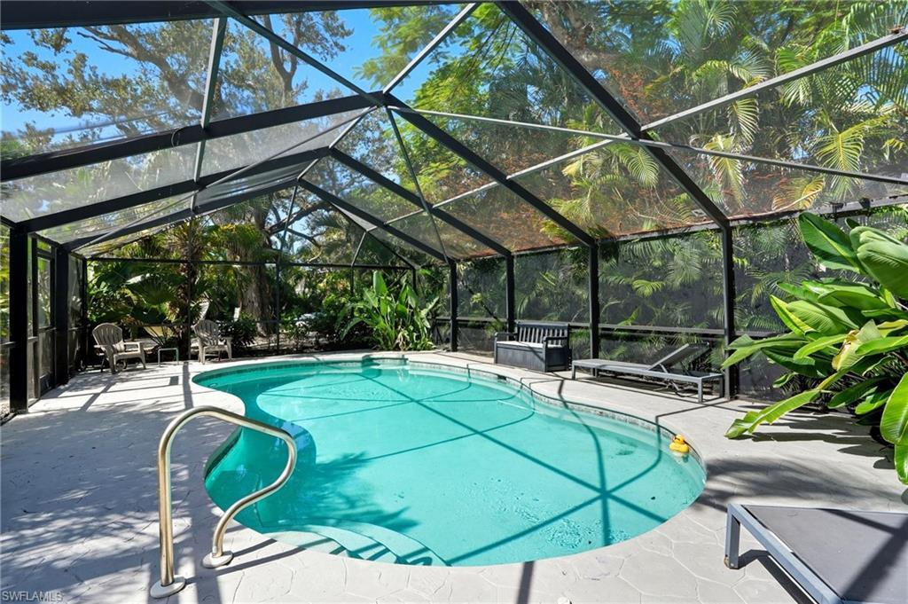 Image 2: Swimming pool featuring glass enclosure, a sunroom, and a patio - Virtually Edited Image