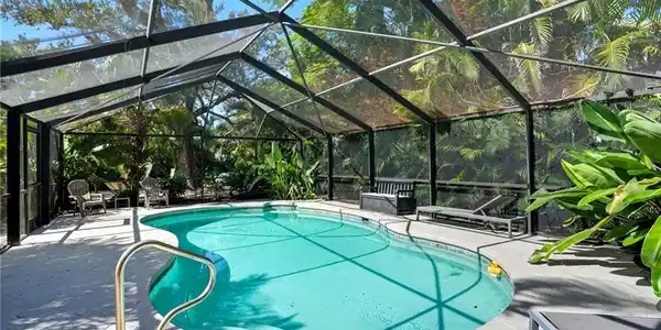 Image 2: Swimming pool featuring glass enclosure, a sunroom, and a patio - Virtually Edited Image