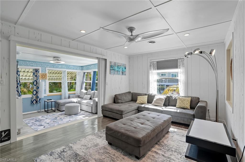 Image 4: Living area with recessed lighting, wood finished floors, ceiling fan, and wood walls - Virtually Edited Image