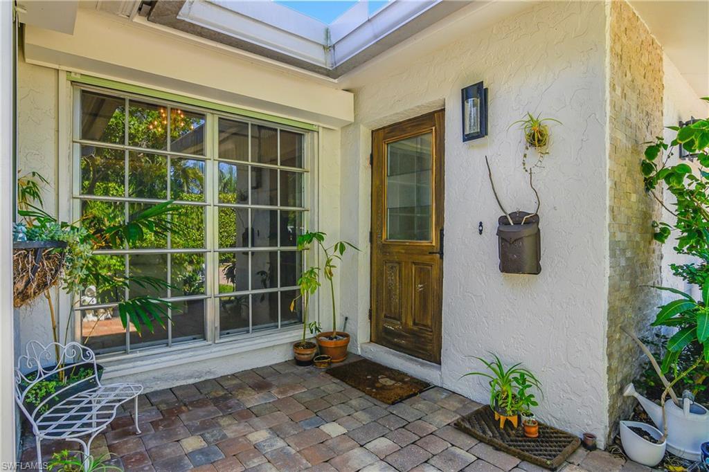 Image 2: Property entrance with stucco siding and a patio area