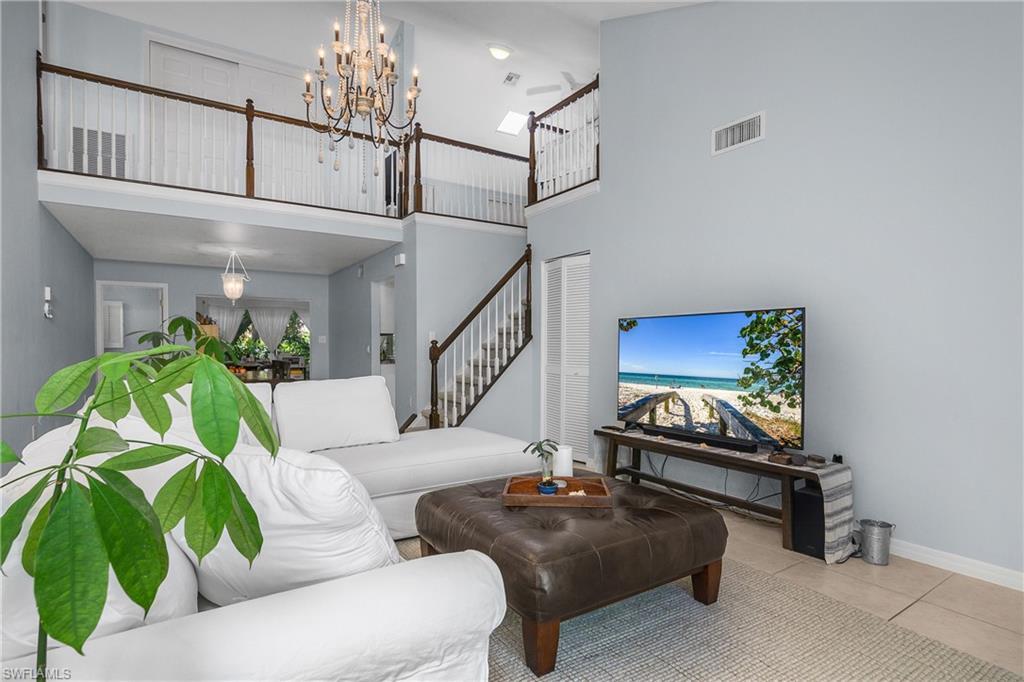 Image 4: Tiled living room with a high ceiling, a chandelier, and stairs