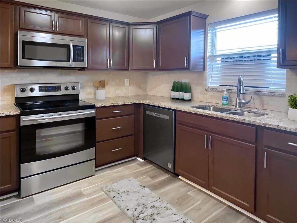 Image 2: Kitchen featuring appliances with stainless steel finishes, light stone countertops, and tasteful backsplash
