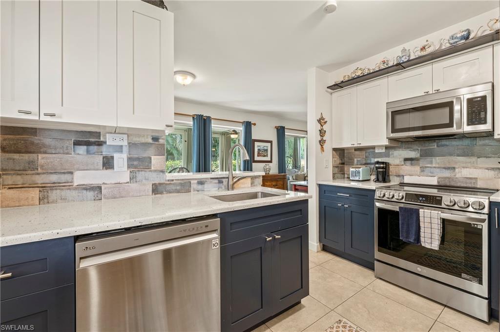 Image 4: The kitchen features white custom cabinets, light tile patterned floors, gorgeous counter tops, tile back splash, and stainless steel appliances