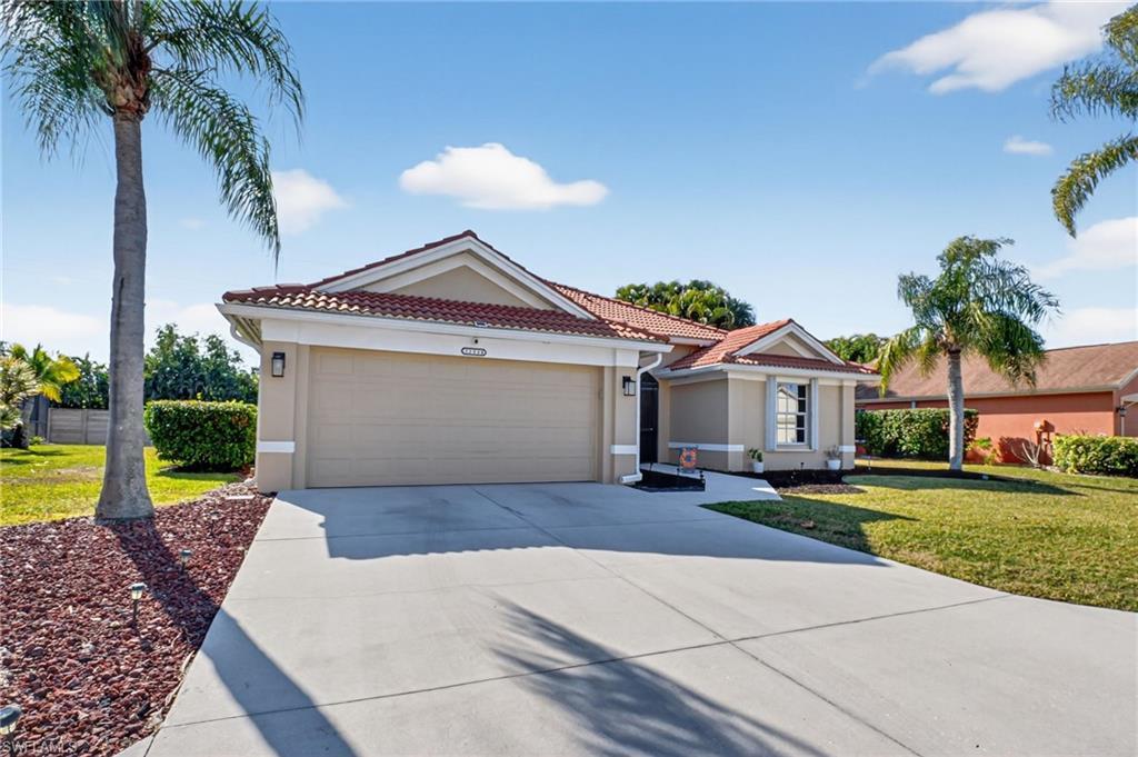 Image 2: View of front facade featuring a front lawn, driveway, and stucco siding