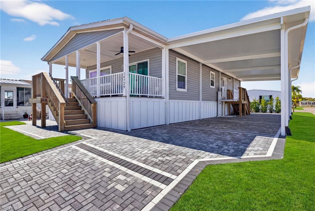 Image 2: Manufactured home with a front yard, a carport, a porch, and decorative paver driveway