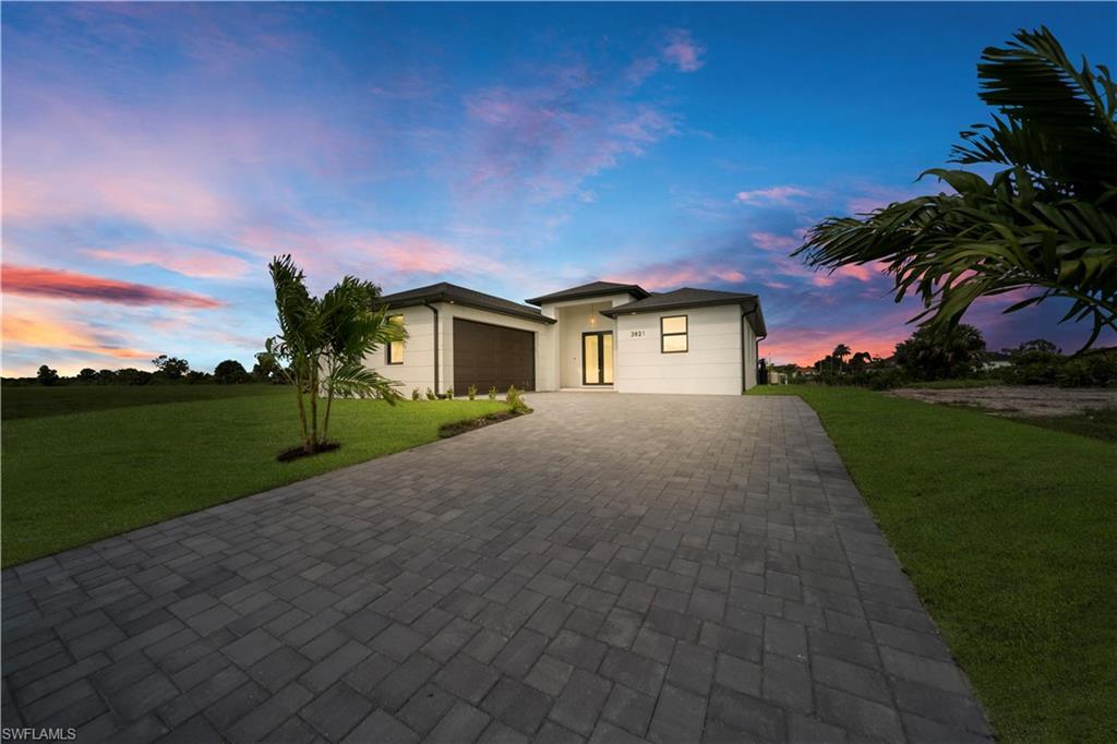 Image 1: View of front of house with a front lawn, decorative driveway, a garage, and stucco siding