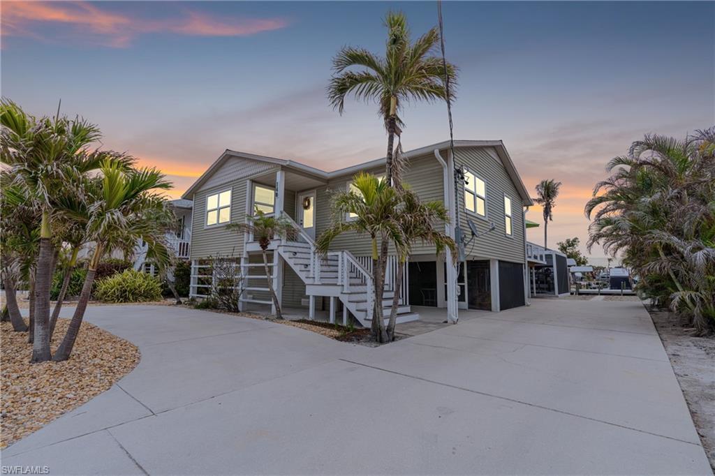 Image 2: Raised beach house featuring concrete driveway and stairway