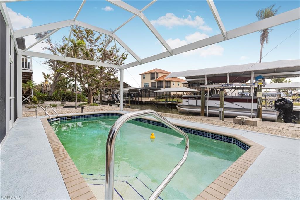 Image 4: Swimming pool featuring boat lift, a water view, a dock, a patio area, and a sunroom