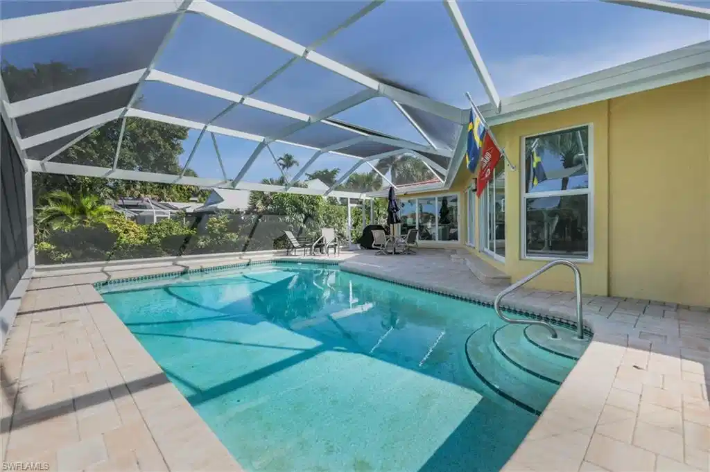 Image 1: Outdoor pool with a patio, screen enclosure, and a sunroom