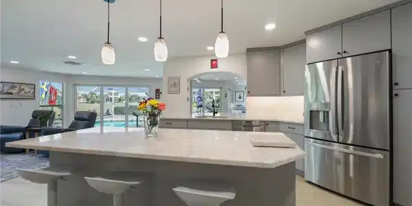 Image 2: Kitchen with gray cabinets, stainless steel appliances, open floor plan, a kitchen breakfast bar, and hanging light fixtures