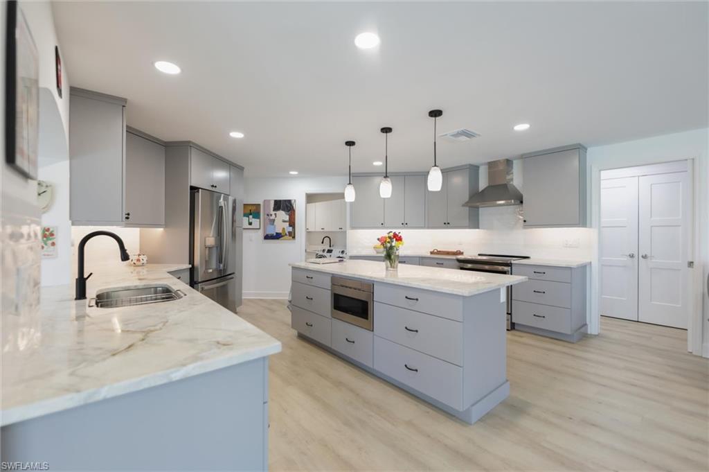 Image 4: Kitchen featuring gray cabinetry, pendant lighting, wall chimney exhaust hood, stainless steel appliances, and recessed lighting