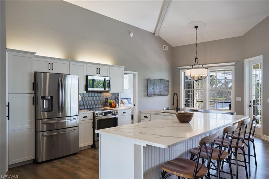 Image 3: Kitchen with stainless steel appliances, a spacious island, tasteful backsplash, and a kitchen breakfast bar