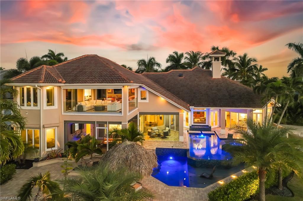 Image 1: Back of house at dusk featuring an outdoor pool, a chimney, an outdoor living space, a patio, and stucco siding