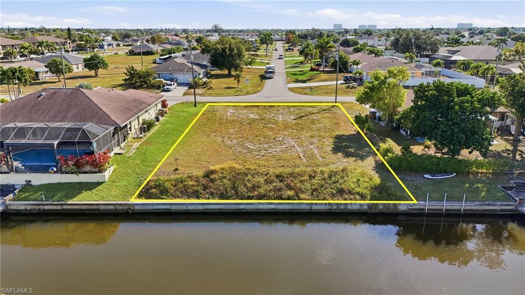 Image 2: Aerial view of residential area featuring property parcel outlined and a nearby body of water
