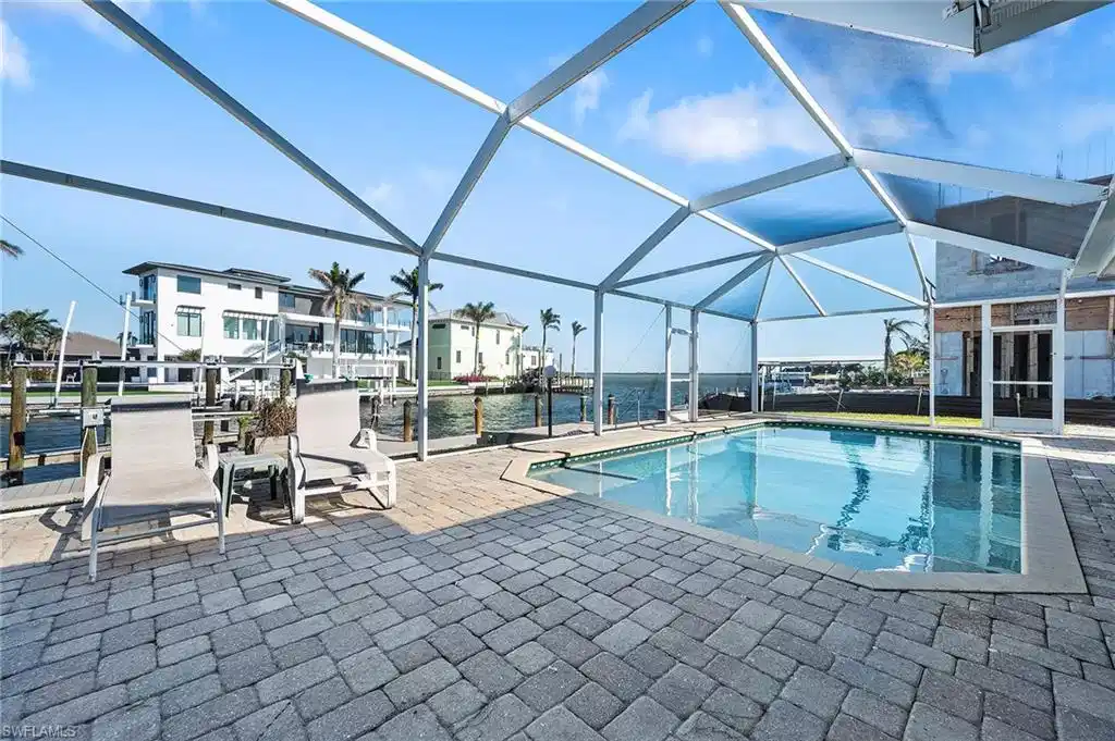 Image 1: View of pool featuring a patio, a water view, and glass enclosure
