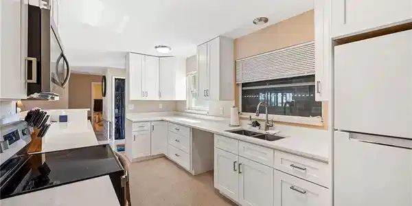 Image 4: Kitchen featuring light carpet, sink, white cabinets, and appliances with stainless steel finishes