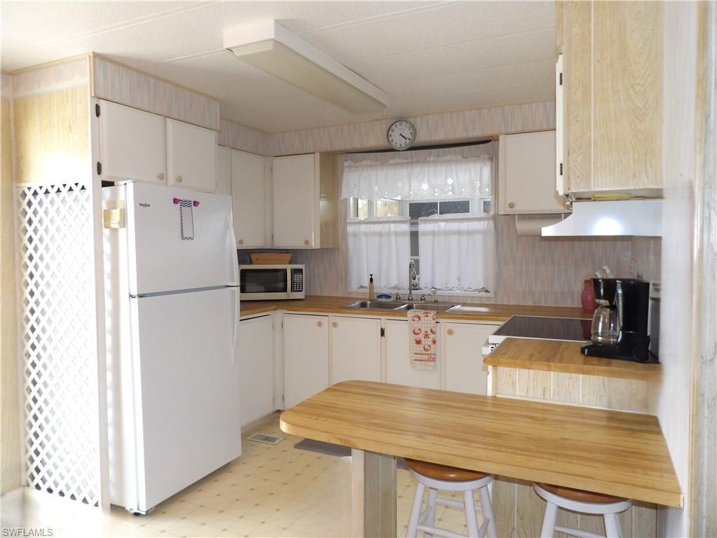 Image 2: Kitchen featuring light flooring, freestanding refrigerator, butcher block counters, stainless steel microwave, and range hood