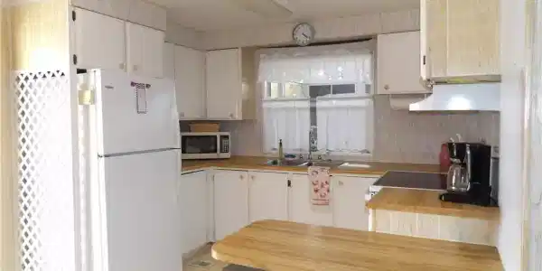 Image 2: Kitchen featuring light flooring, freestanding refrigerator, butcher block counters, stainless steel microwave, and range hood