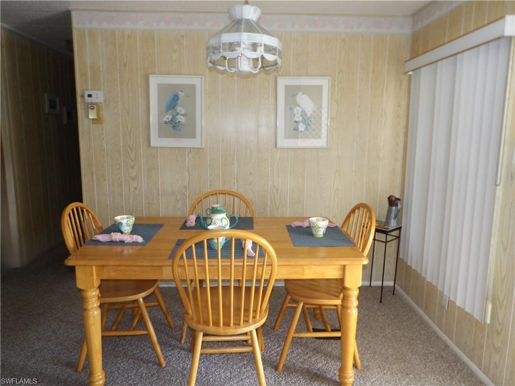 Image 3: Dining room featuring carpet flooring, wood walls, and a chandelier