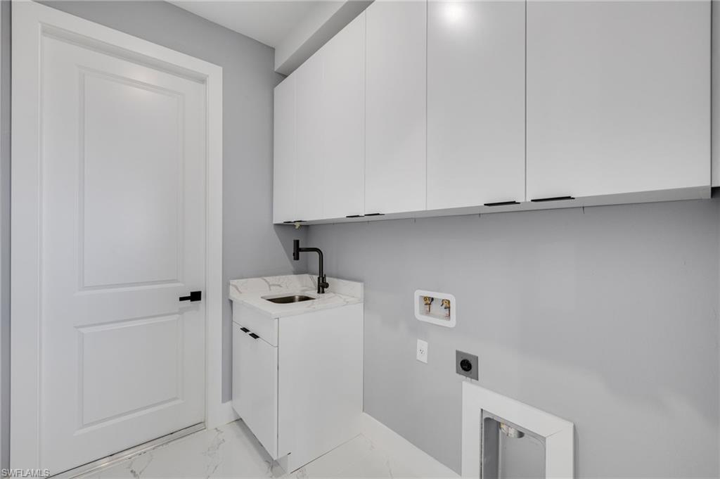 Image 4: Laundry room with light marble finish flooring, upper cabinets, deep laundry sink, and washer/dryer hookups