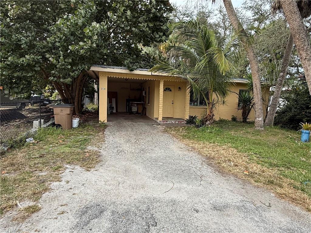Image 1: View of front of home featuring driveway, stucco siding, and a carport