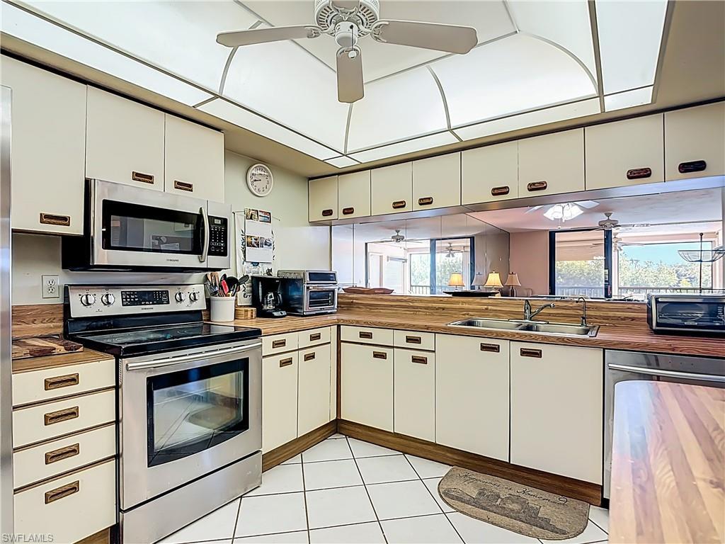 Image 4: Kitchen with stainless steel appliances, a ceiling fan, and white cabinetry