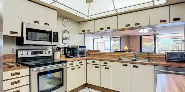 Image 4: Kitchen with stainless steel appliances, a ceiling fan, and white cabinetry