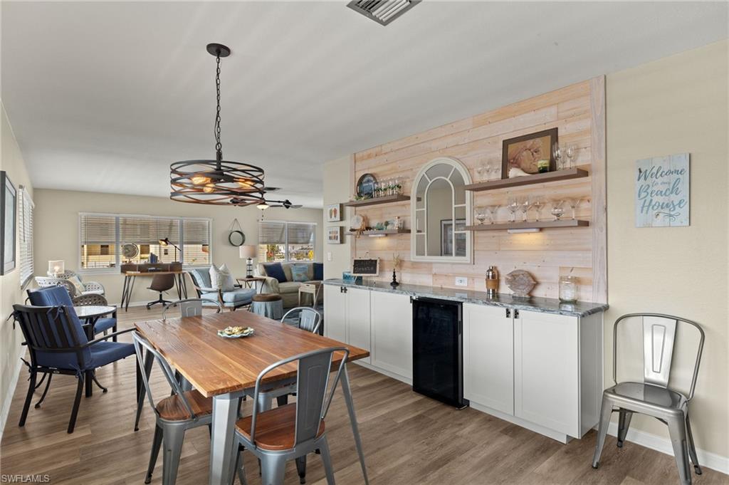 Image 1: Dining space featuring light wood-style floors, wine cooler, and visible vents